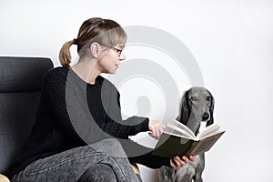 Beautiful woman reading book with her dog. greyhound sduty read
