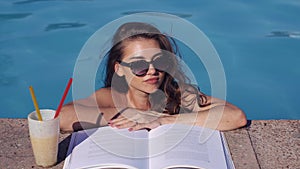 Beautiful woman reading book into swimming pool. Top view