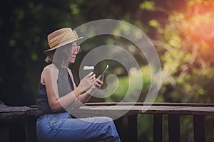 beautiful woman reading message on smart phone and holding coffee cup sitting on outdoor terrace