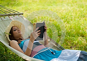 Beautiful woman reading & relaxing in hammock