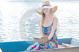 Beautiful woman reading in a row boat on a lake.