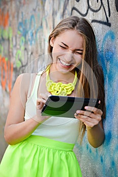 Beautiful woman reading on tablet pc at graffiti
