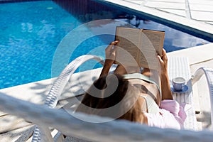 beautiful woman reads a book near the pool.