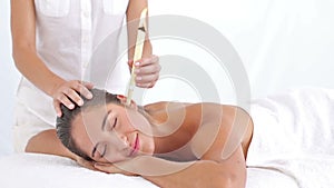 Beautiful woman receiving ear candle treatment at spa center