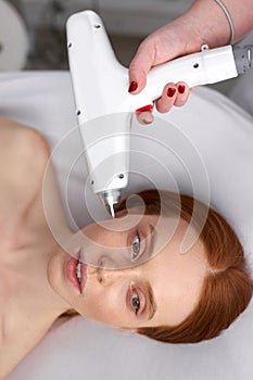 Beautiful woman receiving facial microcurrent treatment by beauty therapist photo