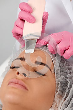 Beautiful woman receiving ultrasound cavitation facial peeling. Cosmetology and facial skin care