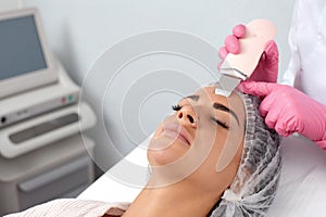 Beautiful woman receiving ultrasound cavitation facial peeling. Cosmetology and facial skin care