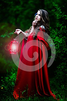 Beautiful woman with red cloak in the woods