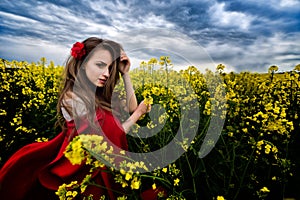 Beautiful woman with red cloak in yellow blooming field