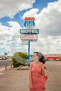 Beautiful woman in red dress on famous Highway under popular sign Route 66