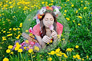 Beautiful woman in a red dress lying on meadow with yellow flowers