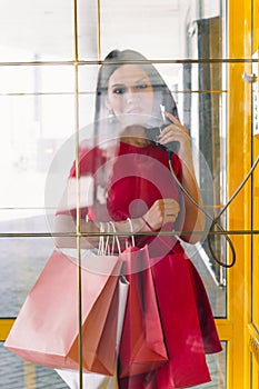 Beautiful woman in red dress orders a taxi in a retro phone booth in the mall after shopping