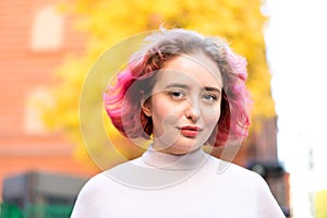 Beautiful woman with red dyed hair and background of autumn yellow leaves.