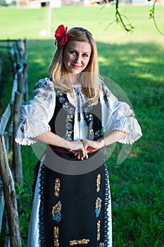 Beautiful woman with red flower in her hair posing in Romanian t