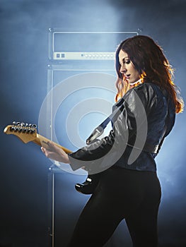 Beautiful woman with red hair playing electric guitar