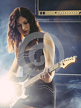 Beautiful woman with red hair playing electric guitar