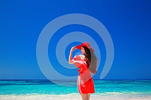 Beautiful woman with red hat enjoying on tropical beach, fashion