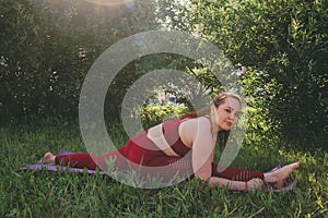 Beautiful woman in red leggings and a top practicing yoga in a city park