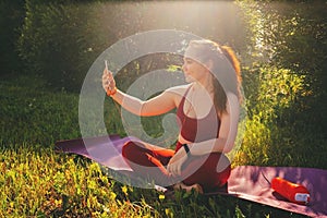 Beautiful woman in red leggings and a top practicing yoga in a city park