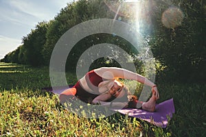 Beautiful woman in red leggings and a top practicing yoga in a city park