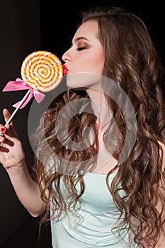 Beautiful woman with red lips eats a big candy sweet lollipop