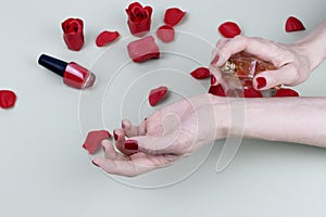 Beautiful woman with red manicure applying perfume on her wrist