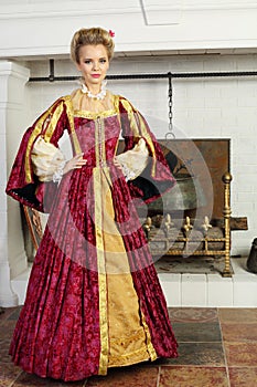 Beautiful woman in red medieval costume stands photo