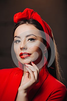 Beautiful woman in red. Stylish model with red lipstick on the lips, bright nail polish. Girl in a suit with a retro headdress