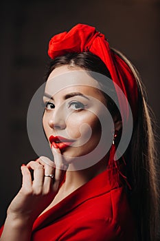 Beautiful woman in red. Stylish model with red lipstick on the lips, bright nail polish. Girl in a suit with a retro headdress