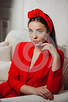 Beautiful woman in red. Stylish model with red lipstick on the lips, bright nail polish. Girl in a suit with a retro headdress