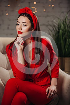 Beautiful woman in red. Stylish model with red lipstick on the lips, bright nail polish. Girl in a suit with a retro headdress