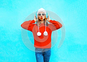 Beautiful woman in red sweater, listens to music in wireless headphones