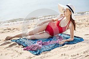 Beautiful woman in red swimsuit is sunbathing on the beach