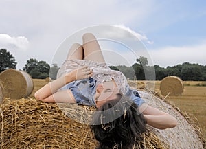 Beautiful woman relaxing on bale of hay