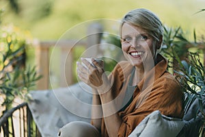 Beautiful woman relaxing in the garden, drinking cup of coffee. Mother having moment to herself while her child is