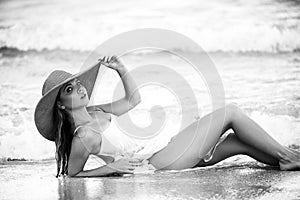 Beautiful woman relaxing in hat in sea. Hot summer day and bright sunny light. Blonde girl having fun on the beach on