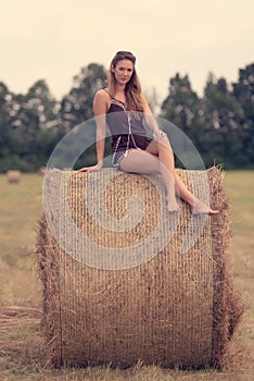 Beautiful woman relaxing on hay bale