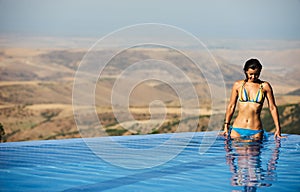 Beautiful woman is relaxing in an infinity pool