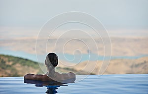 Beautiful woman is relaxing in an infinity pool