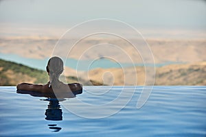 Beautiful woman is relaxing in an infinity pool