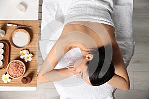 Beautiful woman relaxing on massage table in spa salon, top view