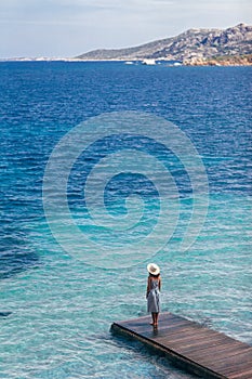 Beautiful woman relaxing on pier in Sardinia island, Italy