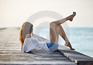 beautiful woman relaxing on pier with sea view