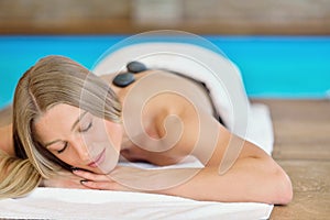 Beautiful woman relaxing in spa salon with hot stones on body. Beauty treatment therapy