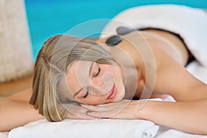 Beautiful woman relaxing in spa salon with hot stones on body. Beauty treatment therapy