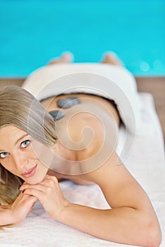 Beautiful woman relaxing in spa salon with hot stones on body. Beauty treatment therapy