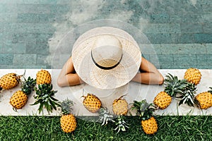 Beautiful Woman Relaxing In Swimming Pool With Pineapples.