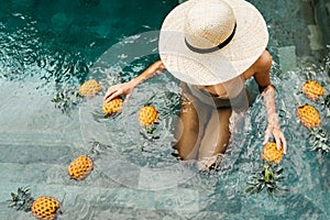 Beautiful Woman Relaxing In Swimming Pool With Pineapples. Healthy Lifestyle, Nutrition, Diet. Summer Vacation