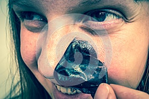 Beautiful woman removes black nose mask - skin care concept