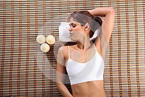 Beautiful woman resting on bamboo mat in spa